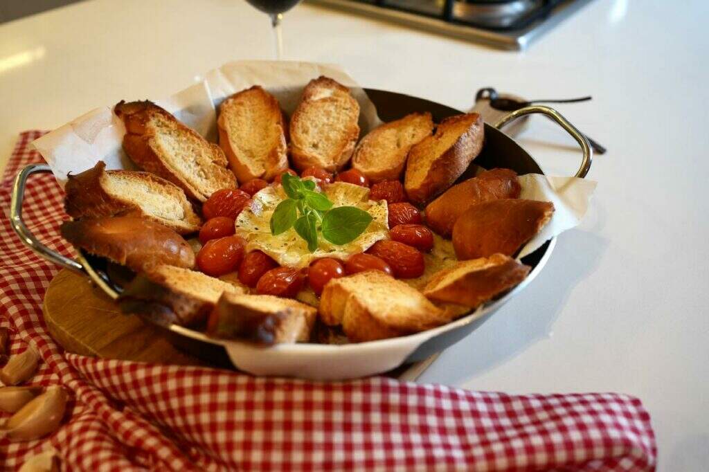 Aperitivo de queijo camembert, tomate cereja e pão baguete